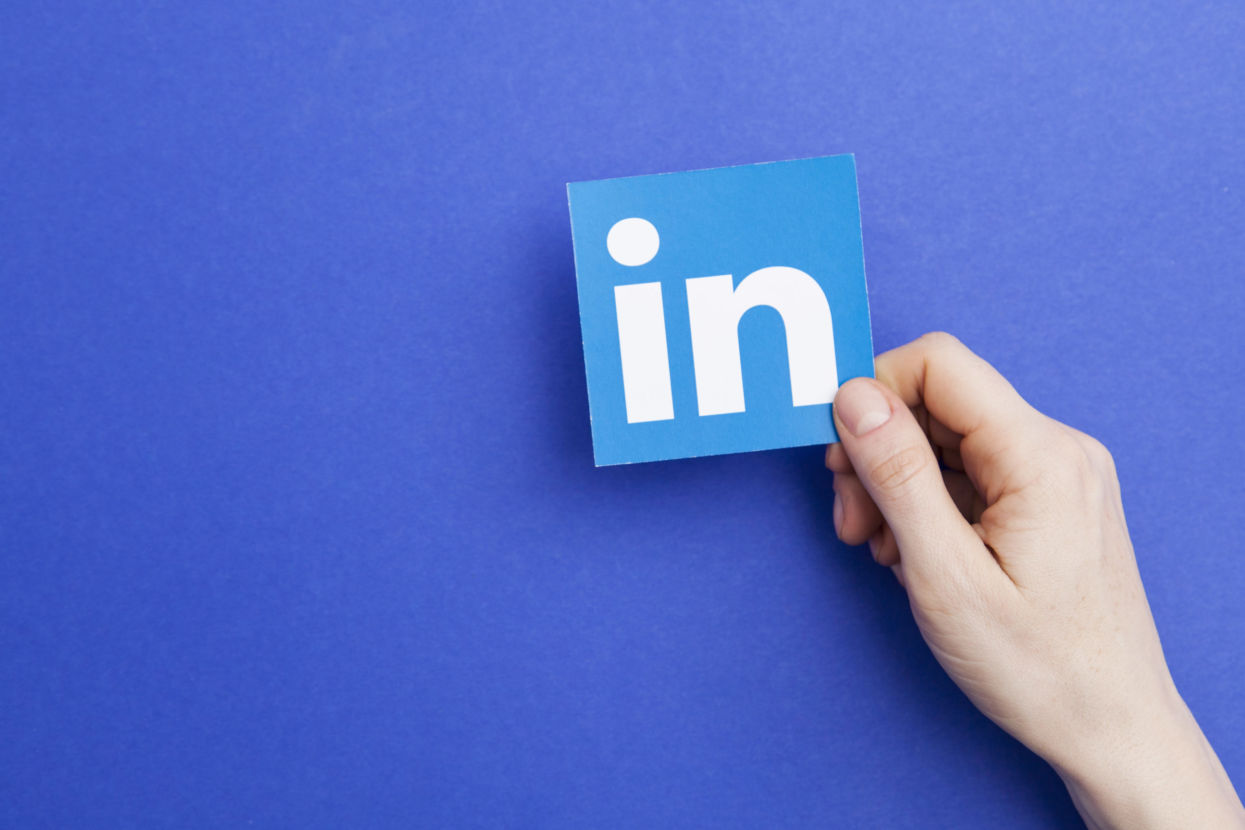 Person holding up printed LinkedIn logo