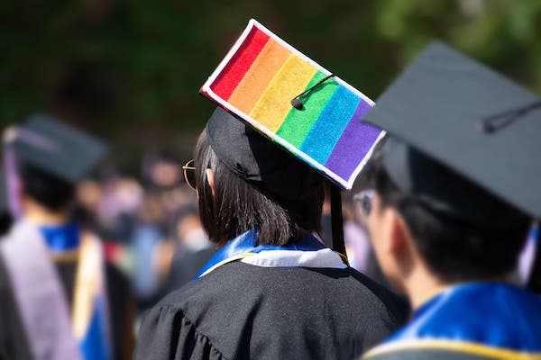 A graduate sports LGBTQ colors on their cap.