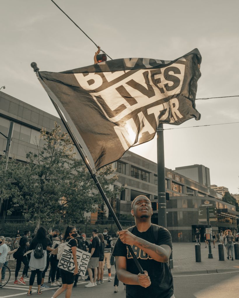 The New Word is equality. A man waving a "Black Lives Matter" flag