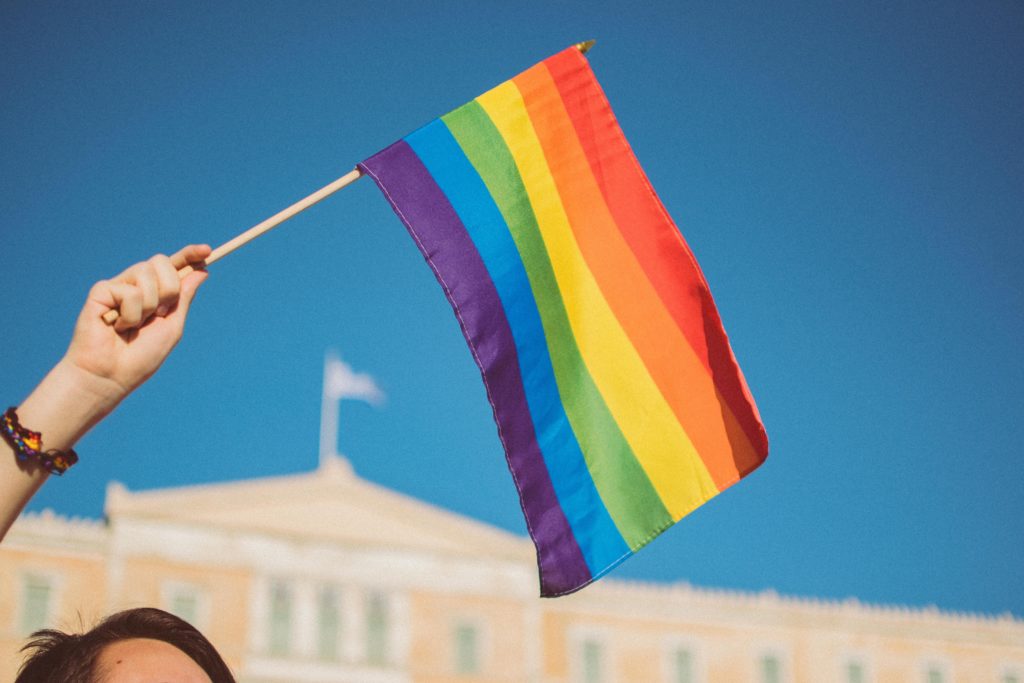 The New Word is "Allyship." A photo of someone waving a pride flag