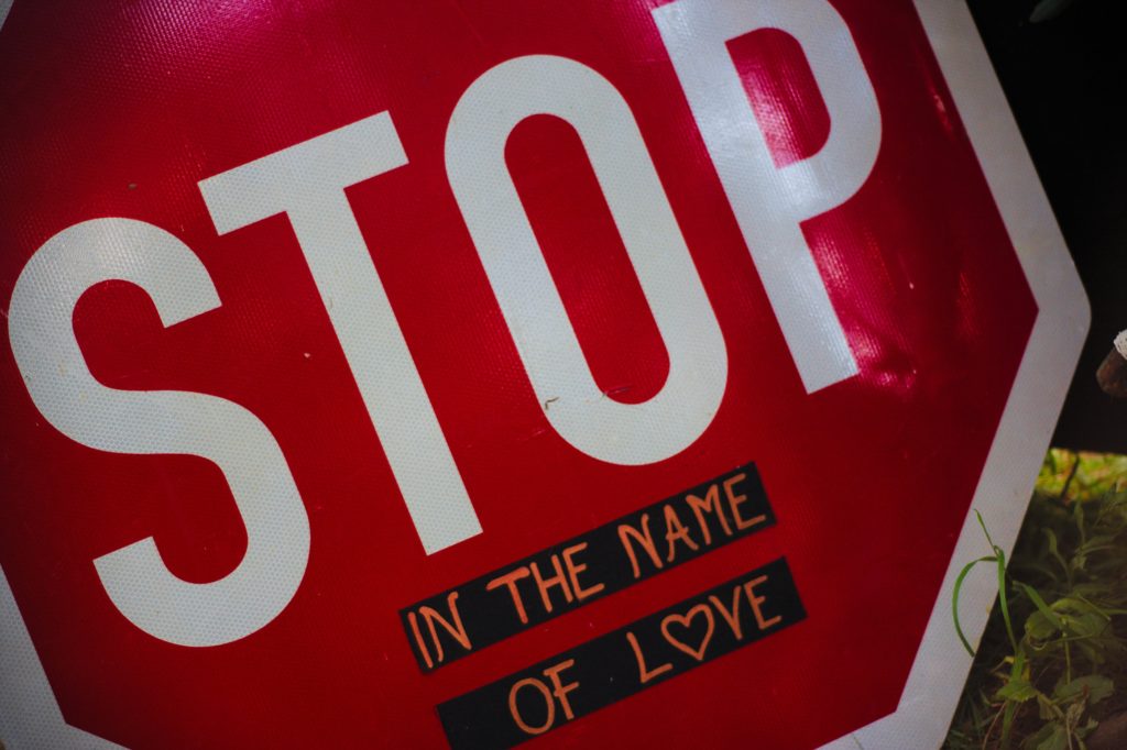 A stop sign with graffiti that reads, "STOP: in the name of love."