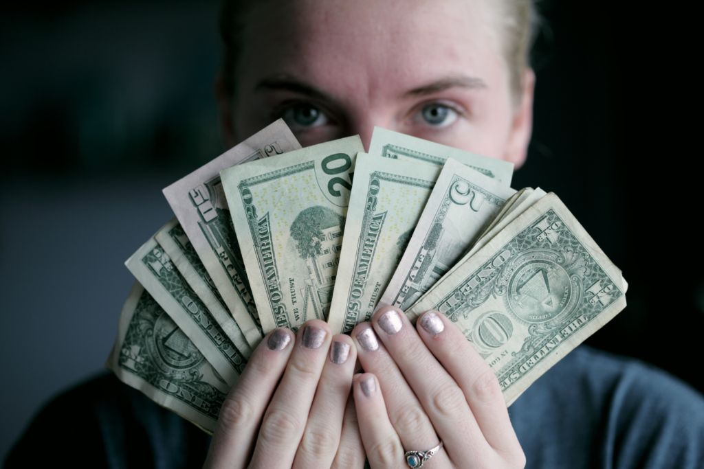 A photo of a woman holding money, highlighting the gender pay gap.