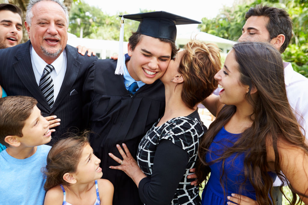 A happy Latinx family celebrates a new college grad. To help students from underserved communities, reaching out to the whole family is key.