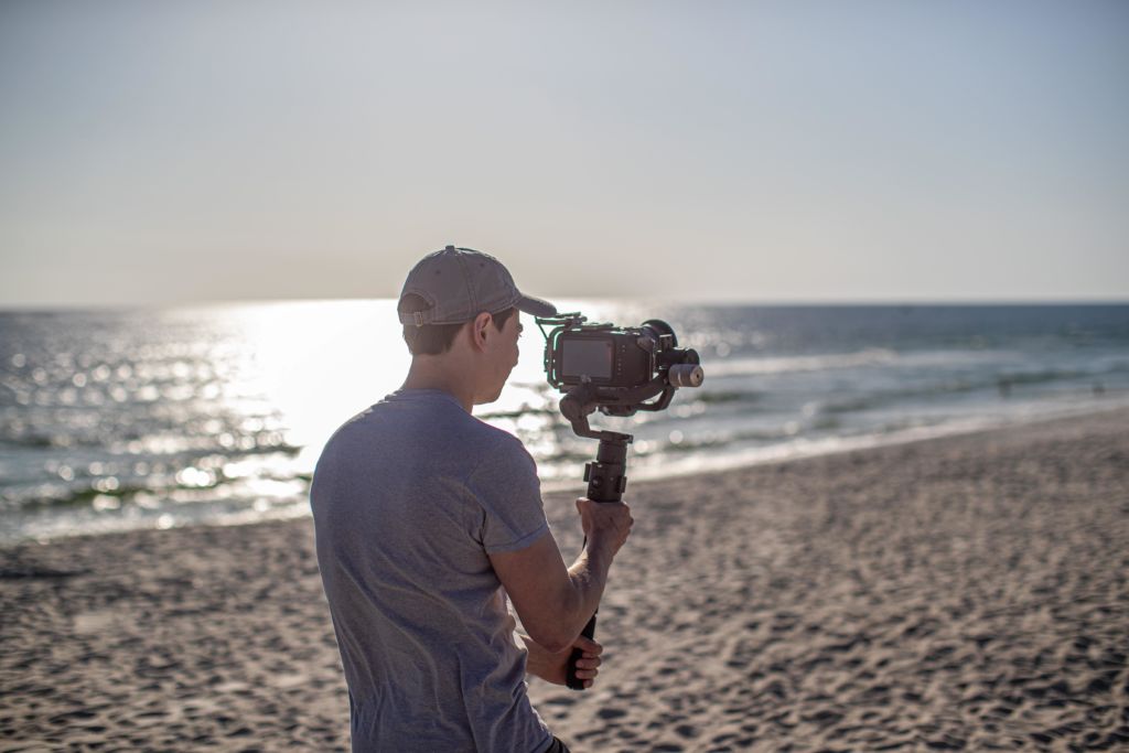 Jake Ammann using a professional camera while at a video shoot on the beach. 