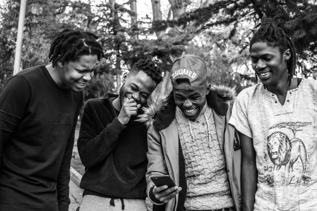 A group of male friends laugh as they check out a phone.