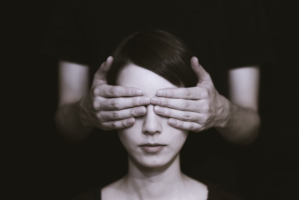 A woman who can't see because hands are covering her eyes