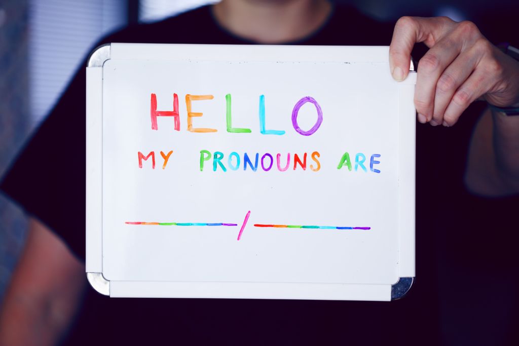 A sign reads, "Hello, my pronouns are ___." Elle pronouns are the new word for Hispanic Heritage Month.