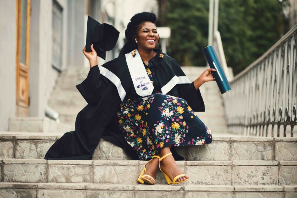A Black female student celebrates her graduation. Black History Month 2023 is important in higher education because it helps students enroll and persist in college.